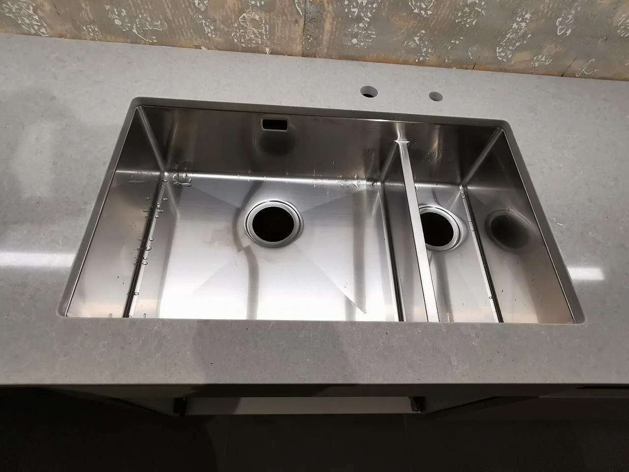 Underlimmad rostfri dubbelho i grå köksbänkskiva av Technistone Noble Concrete Grey i ett kök i Bjärred.