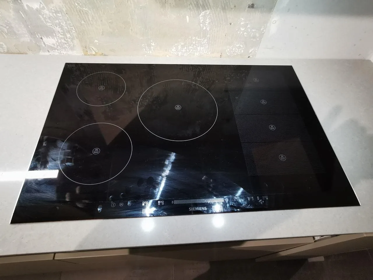 Induktionshäll monterad ovanpå den grå Technistone Noble Concrete Grey-bänkskivan i ett kök i Bjärred.