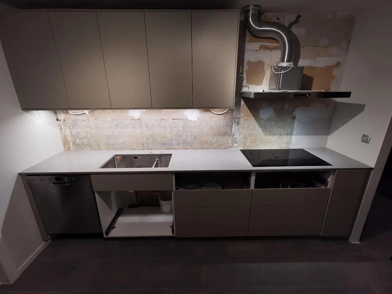 Köksbänkskiva i grå Technistone Noble Concrete Grey, polerad betonglik kvartskomposit, med underlimmad rostfri diskho och induktionshäll i ett kök i Bjärred.