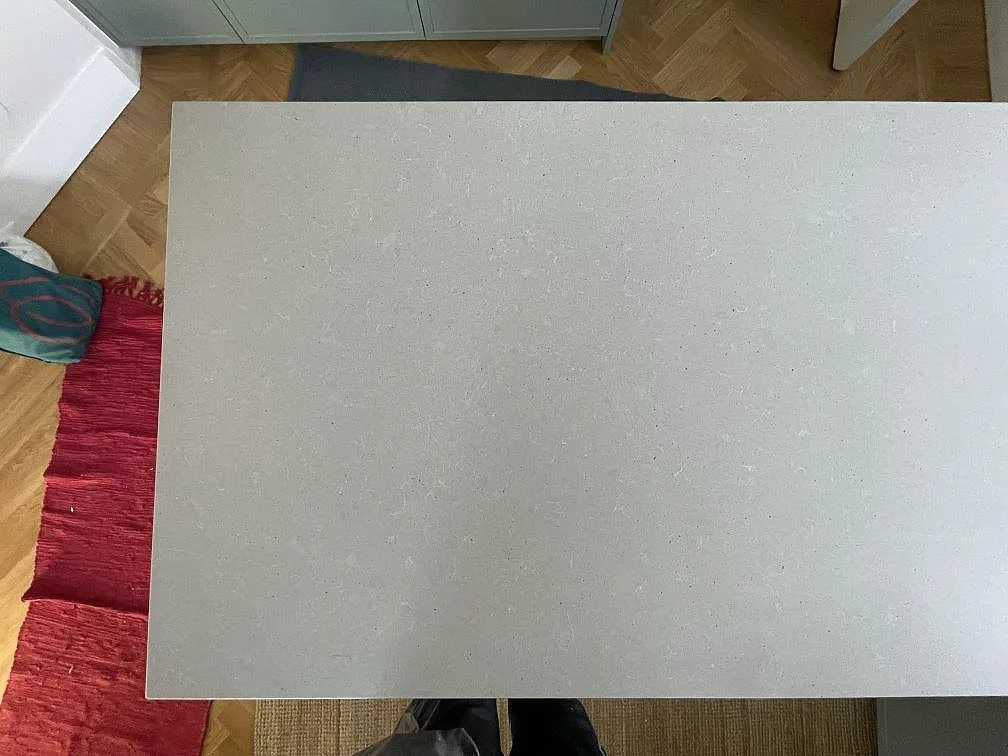 Matt grå köksbänkskiva i Technistone Noble Concrete Grey sedd ovanifrån på halvön, betonglik kvartskomposit med jämn ljusgrå yta, i ett kök i Djursholm.