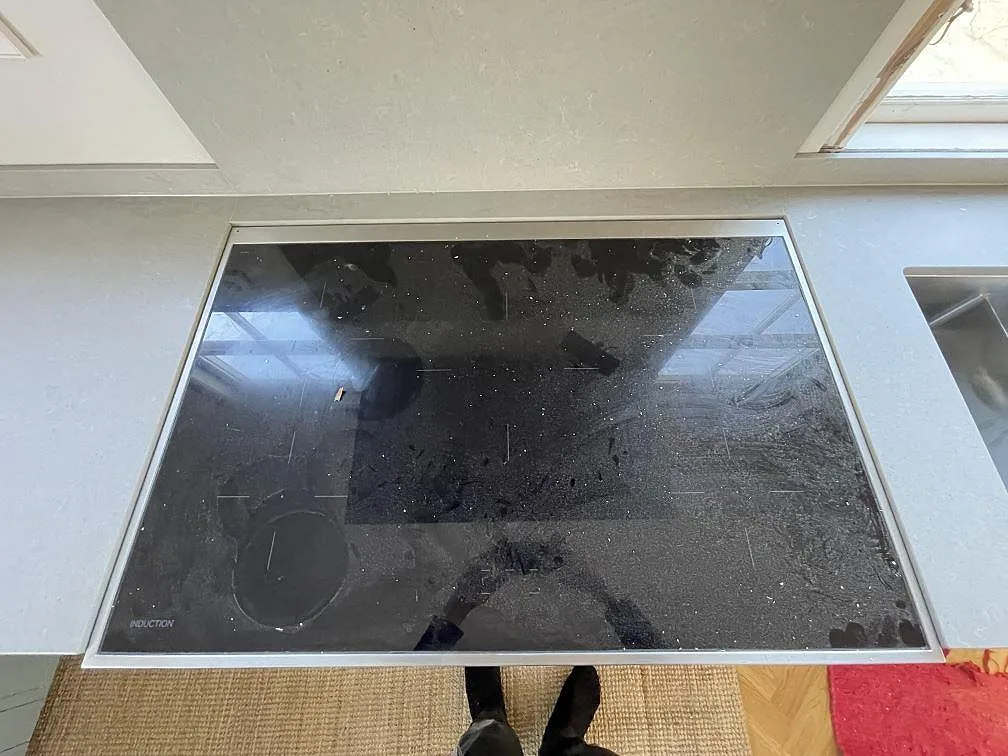 Infälld induktionshäll monterad i ljusgrå matt köksbänkskiva i Technistone Noble Concrete Grey, betonglik kvartskomposit, i ett kök i Djursholm.