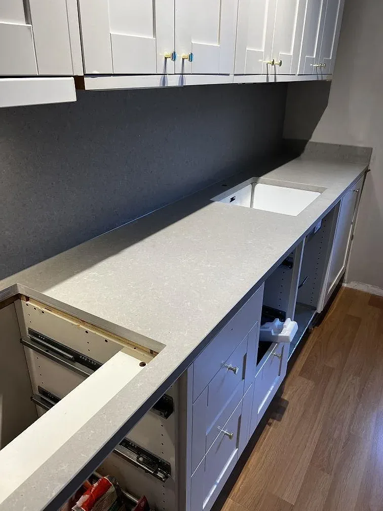 Lång köksbänk i matt grå Technistone Noble Concrete Grey längs grå underskåp under montering, kök i Göteborg.