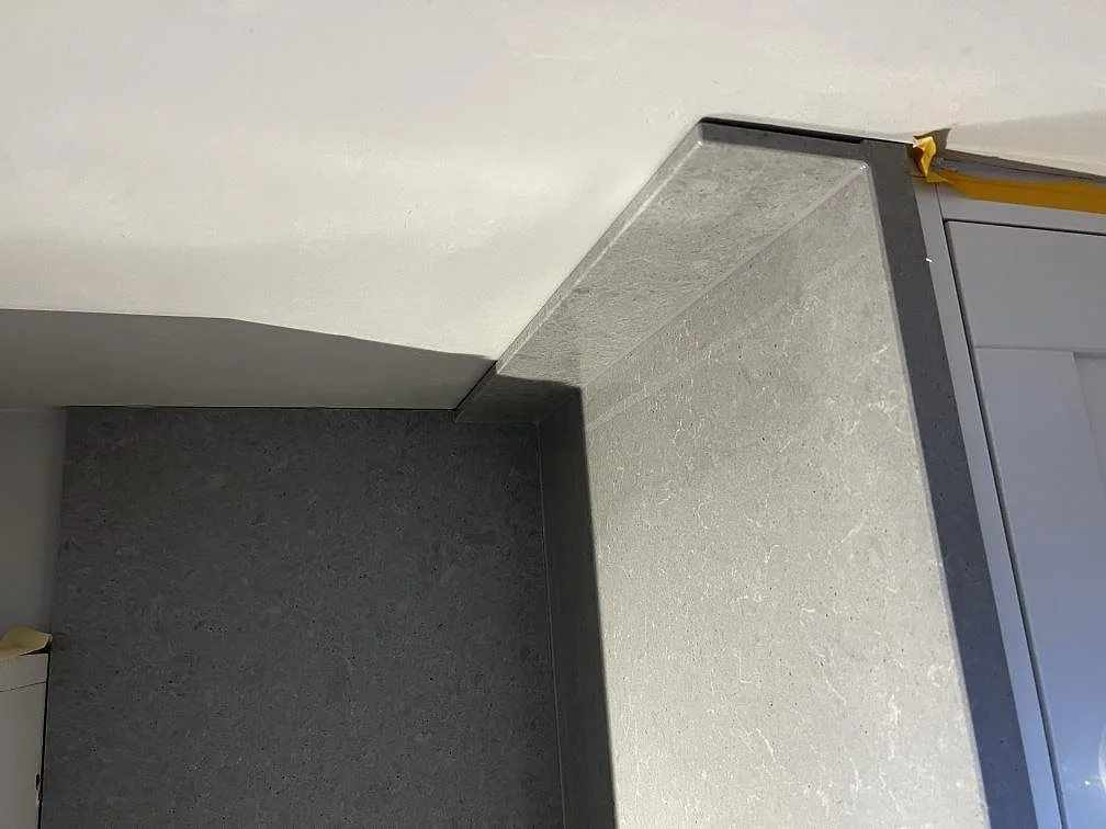 Mitthörn i matt Technistone Noble Concrete Grey där bänkskivan möter ett uppvikt stänkskydd i samma sten, kök i Göteborg.