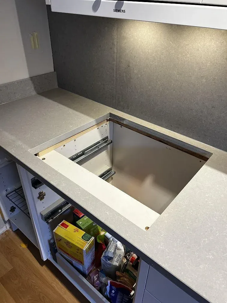 Bänkskiva i matt Technistone Noble Concrete Grey vid en låda under montering, ljusgrå betongkomposit, kök i Göteborg.