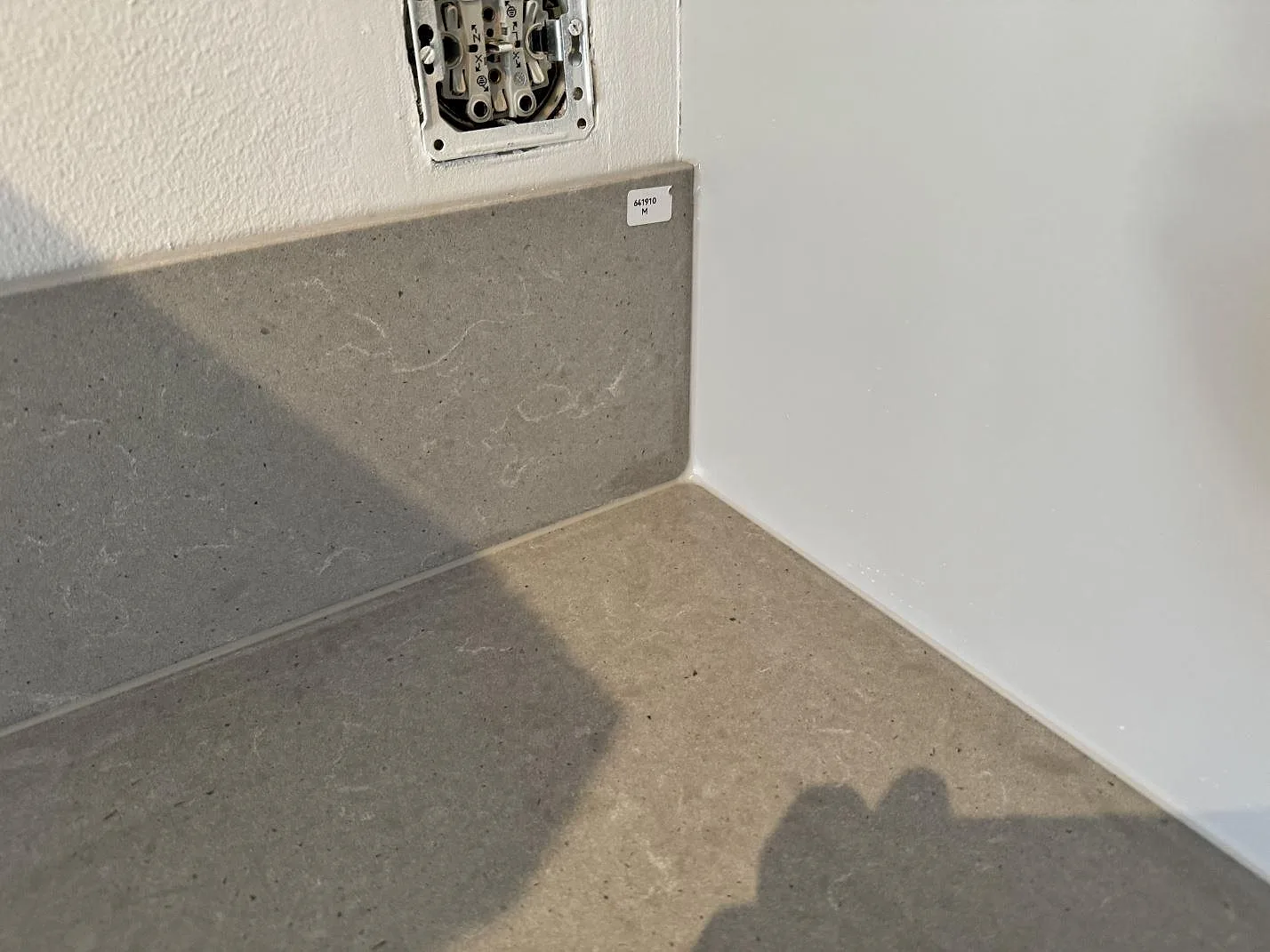 Detalj av hörn och stänkskydd i matt Technistone Noble Concrete Grey under köksmontering i Göteborg.