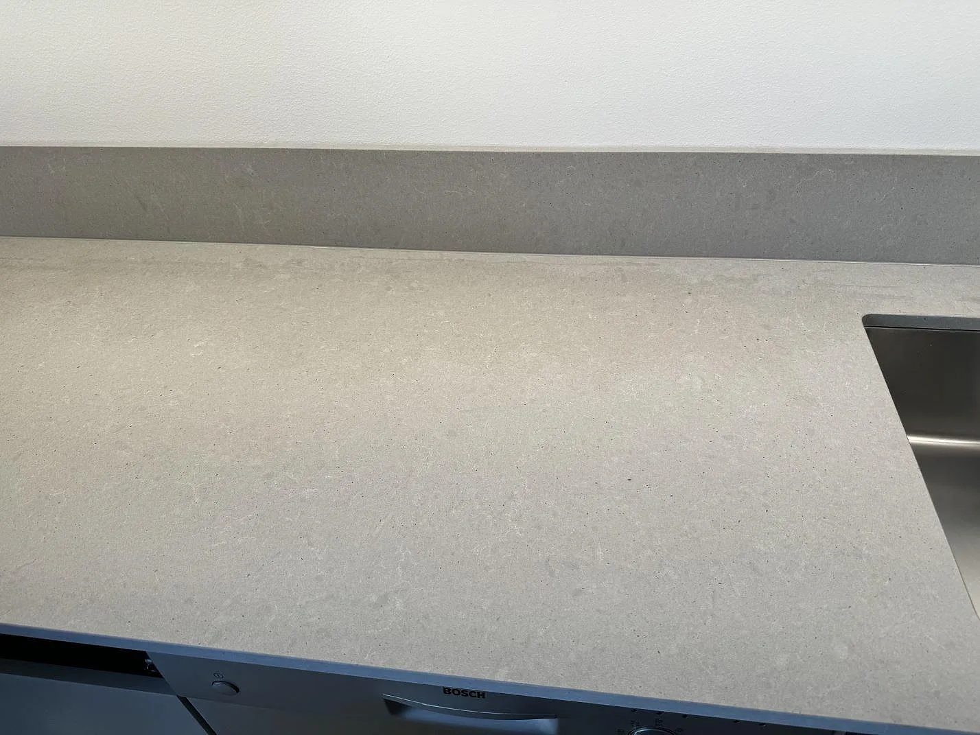 Närbild på arbetsyta i matt Technistone Noble Concrete Grey med stänkskydd och diskho i kanten i Göteborg.