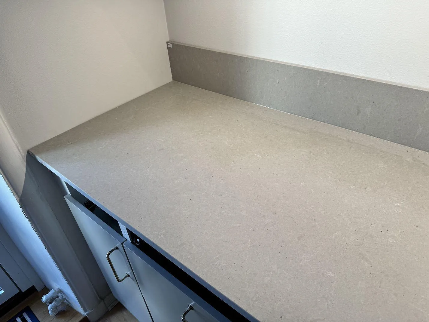 Vänster arbetsyta i matt Technistone Noble Concrete Grey med uppvikt stänkkant ovanför köksstommar i Göteborg.