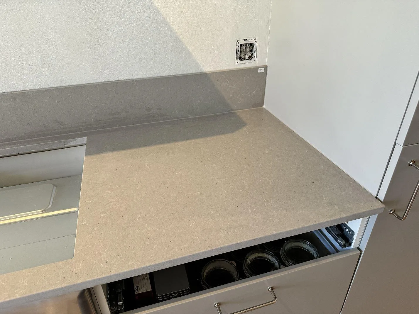 Höger del av köksbänkskiva i matt Technistone Noble Concrete Grey med stänkskydd och vit köksinredning i Göteborg.