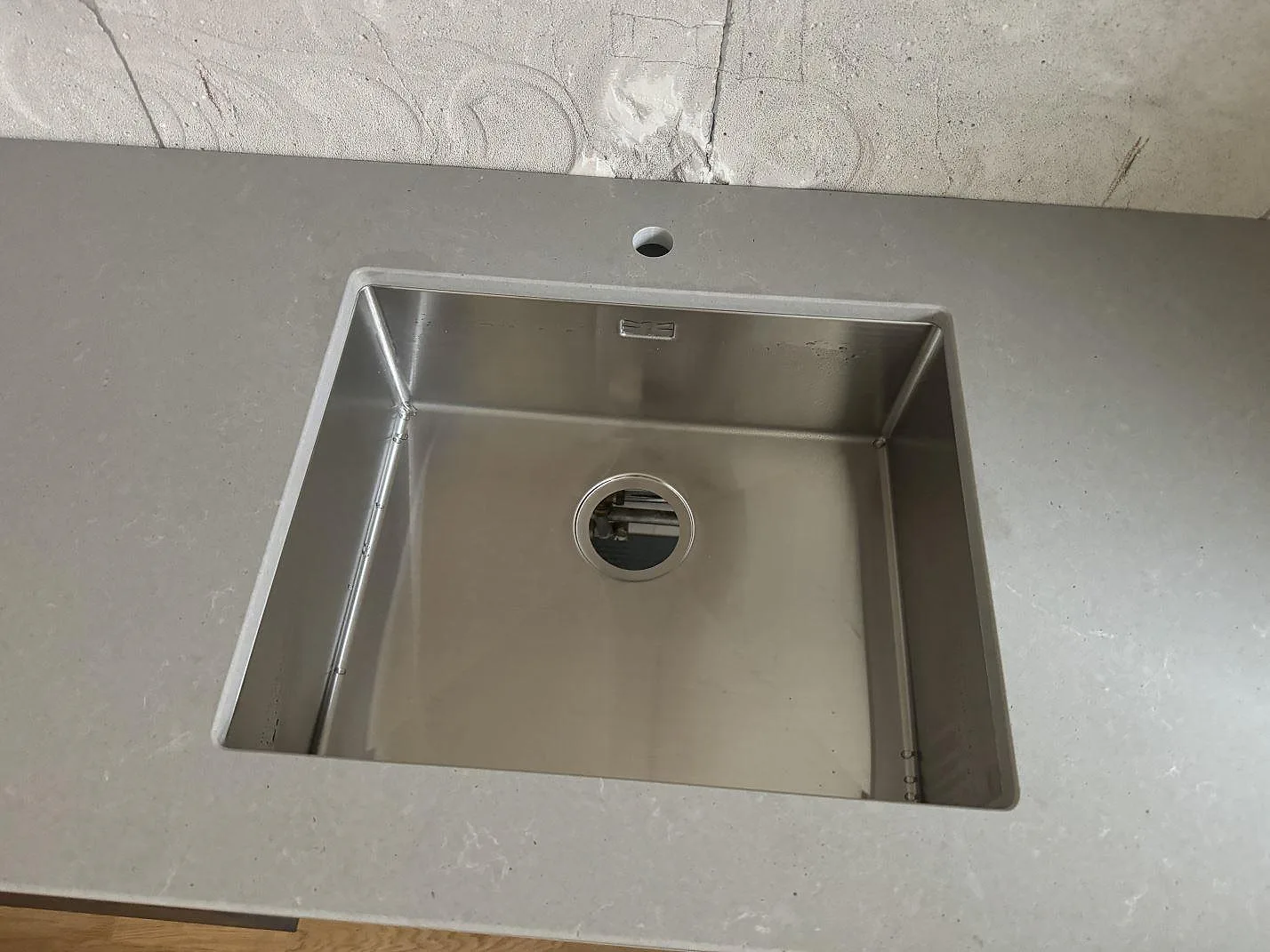 Närbild på rostfri diskho i köksbänkskiva av Technistone Noble Concrete Grey, matt komposit, i Göteborg.