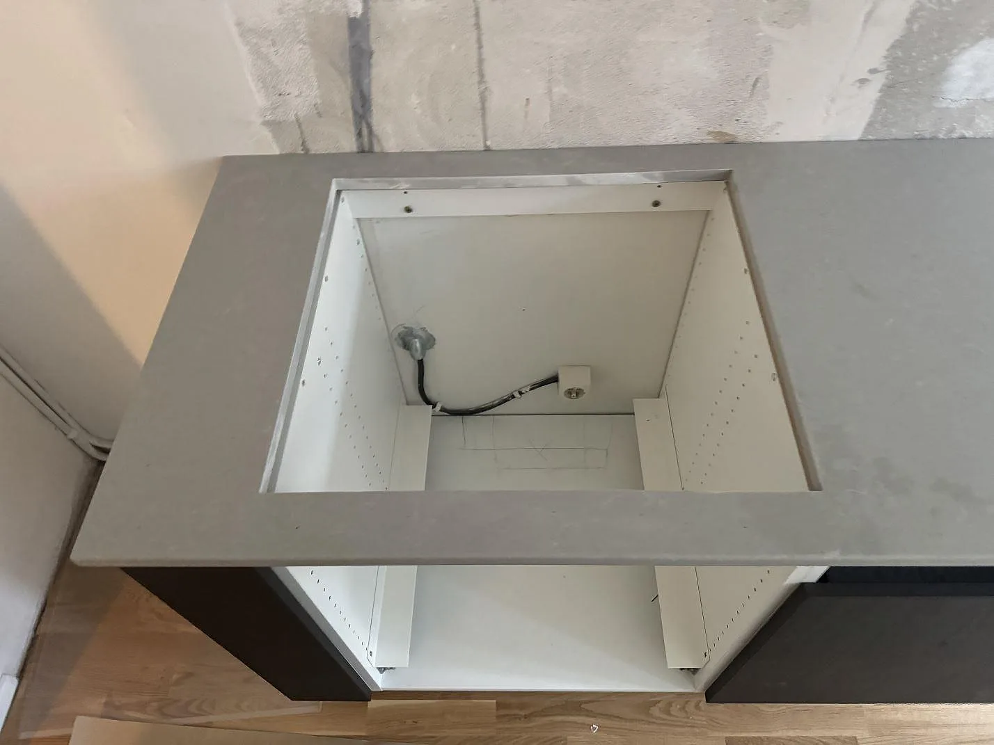 Detalj av rektangulärt urtag i köksbänkskiva av Technistone Noble Concrete Grey, matt kvartskomposit, under montering i Göteborg.