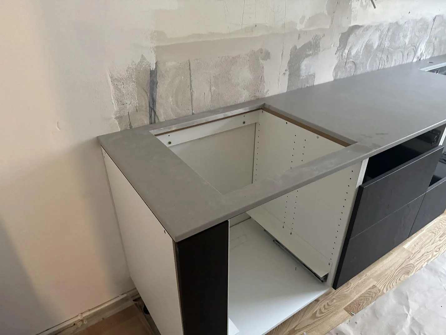 Vinklad bild av köksbänkskiva i Technistone Noble Concrete Grey, matt komposit, med rektangulärt urtag och öppen köksstomme i Göteborg.