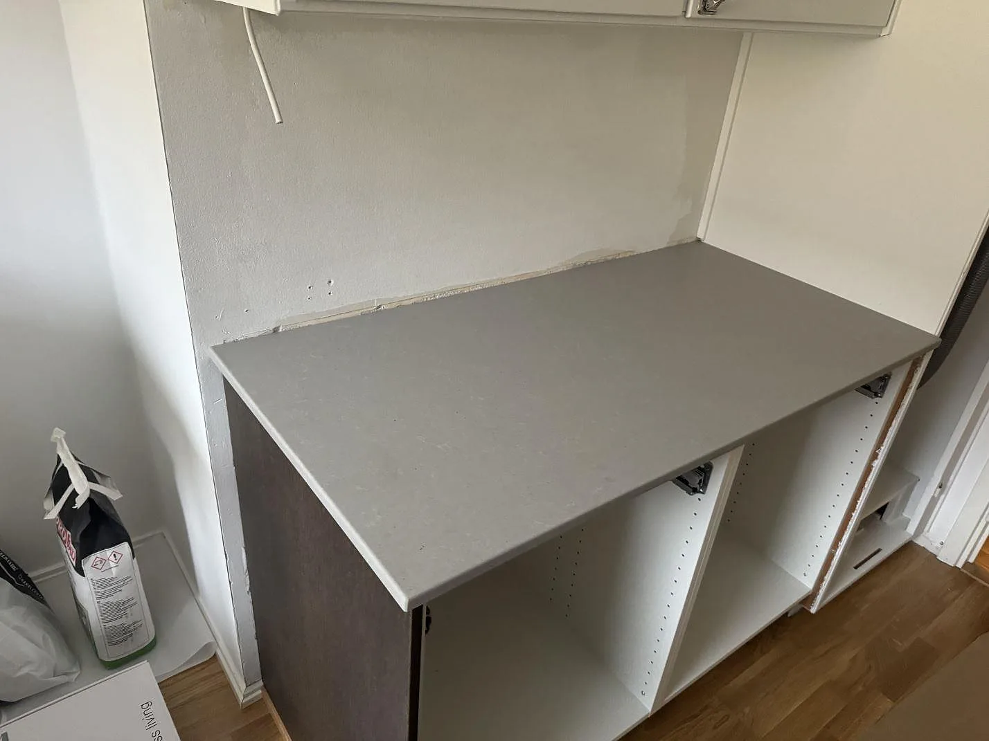 Rak köksbänkskiva i Technistone Noble Concrete Grey, matt komposit, monterad på öppna stommar i Göteborg.