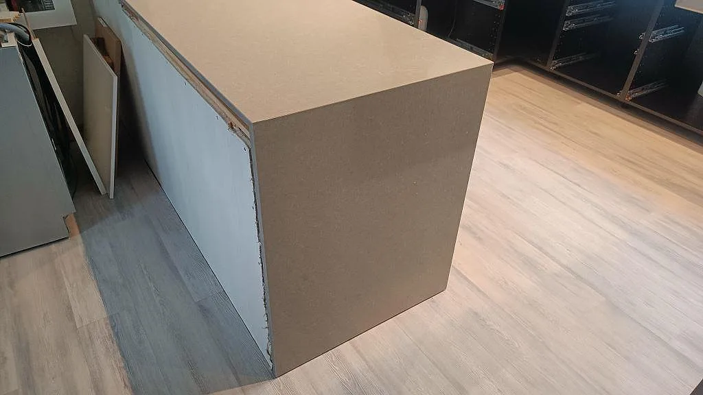 Polerad Technistone Noble Concrete Grey som sammanhållen bänkskiva och gavel på halvön i ett kök under montering i Höllviken.