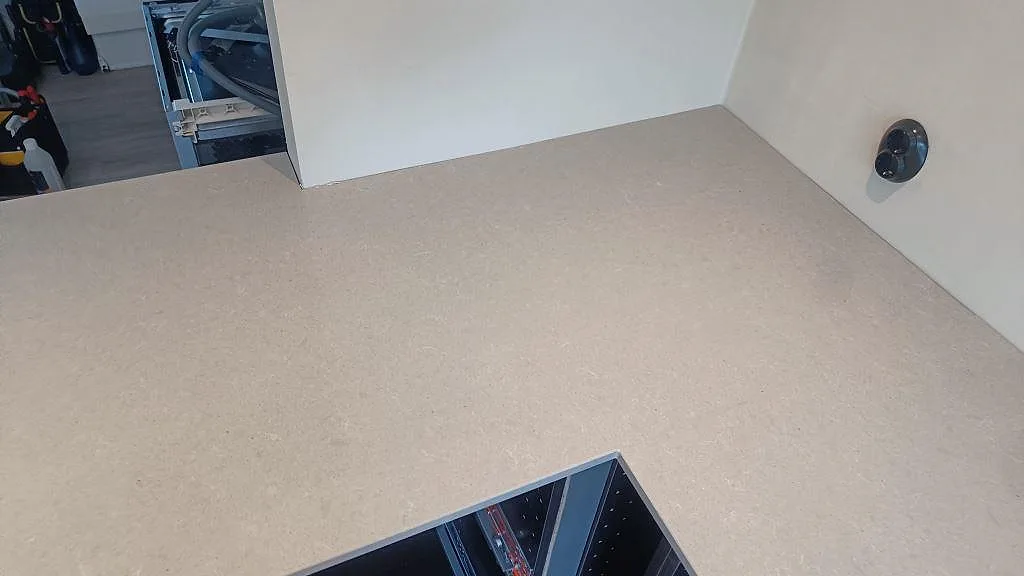 Detalj av hörnet i polerad Technistone Noble Concrete Grey med utskärning och vägguttag i ett kök under montering i Höllviken.