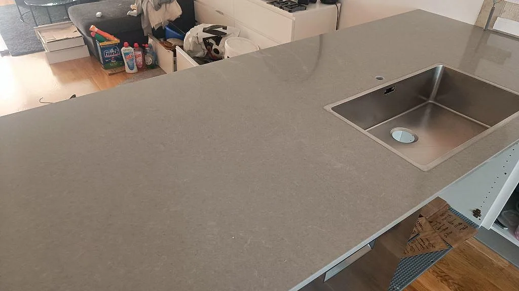 Närbild på grå köksbänkskiva i Technistone Noble Concrete Grey med underlimmad rostfri diskho och halvö i Jönköping.