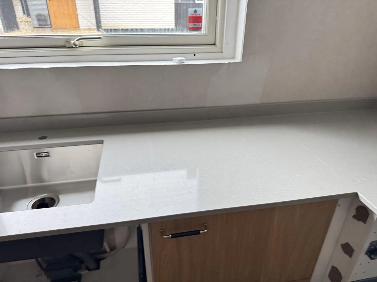 Underlimmad rostfri diskho i en polerad köksbänk i Technistone Noble Concrete Grey under ett fönster i ett kök i Jönköping.