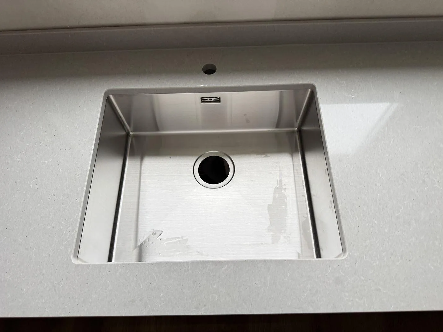 Närbild på underlimmad rostfri enkelho infälld under betonggrå Technistone Noble Concrete Grey i ett kök i Jönköping.