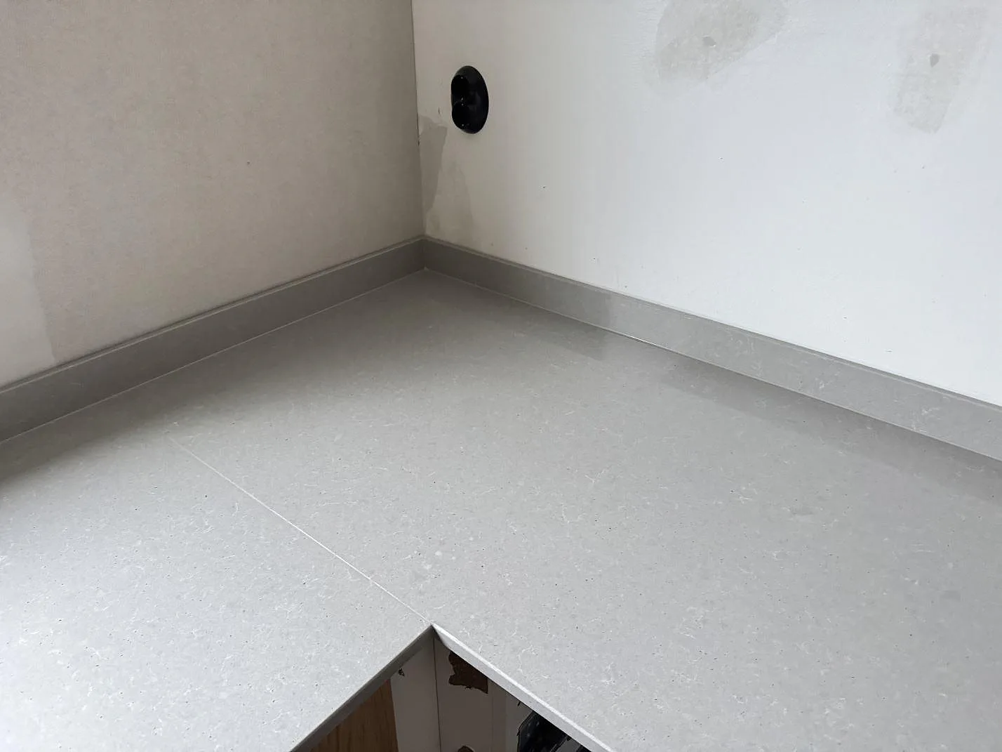Polerad köksbänk i Technistone Noble Concrete Grey i ett hörn mot omålad vägg, monterad under montering i ett kök i Jönköping.