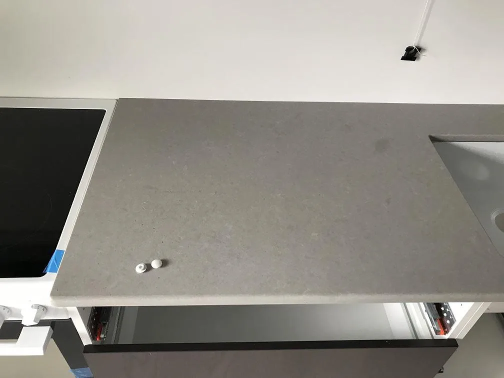 Grå Technistone Noble Concrete Grey-bänkskiva runt en induktionshäll i ett kök i Kågeröd, fotad under montering.