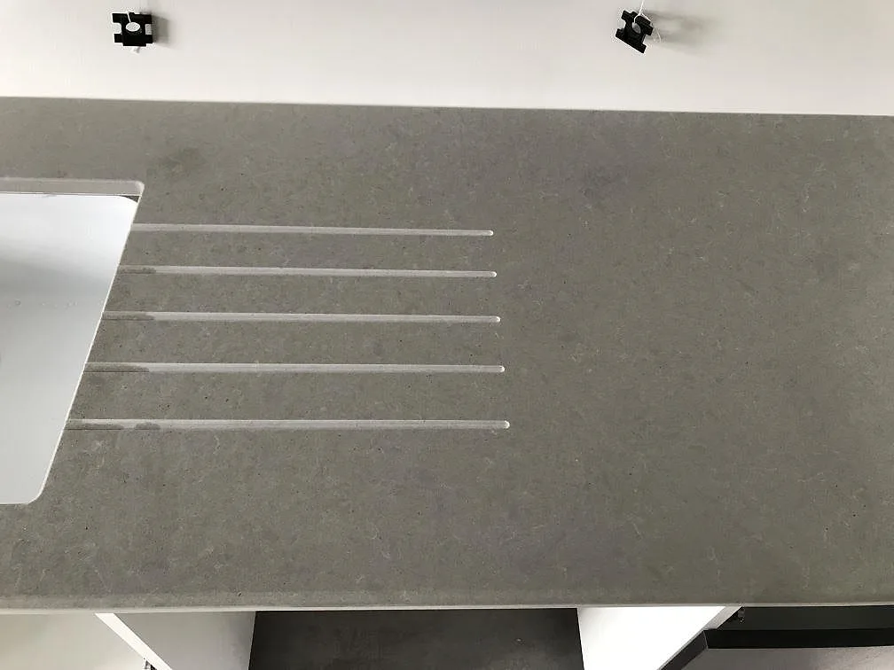 Eye-level-bild av den grå Technistone Noble Concrete Grey-bänkskivan i köket i Kågeröd med infälld induktionshäll och underlimmad diskho.