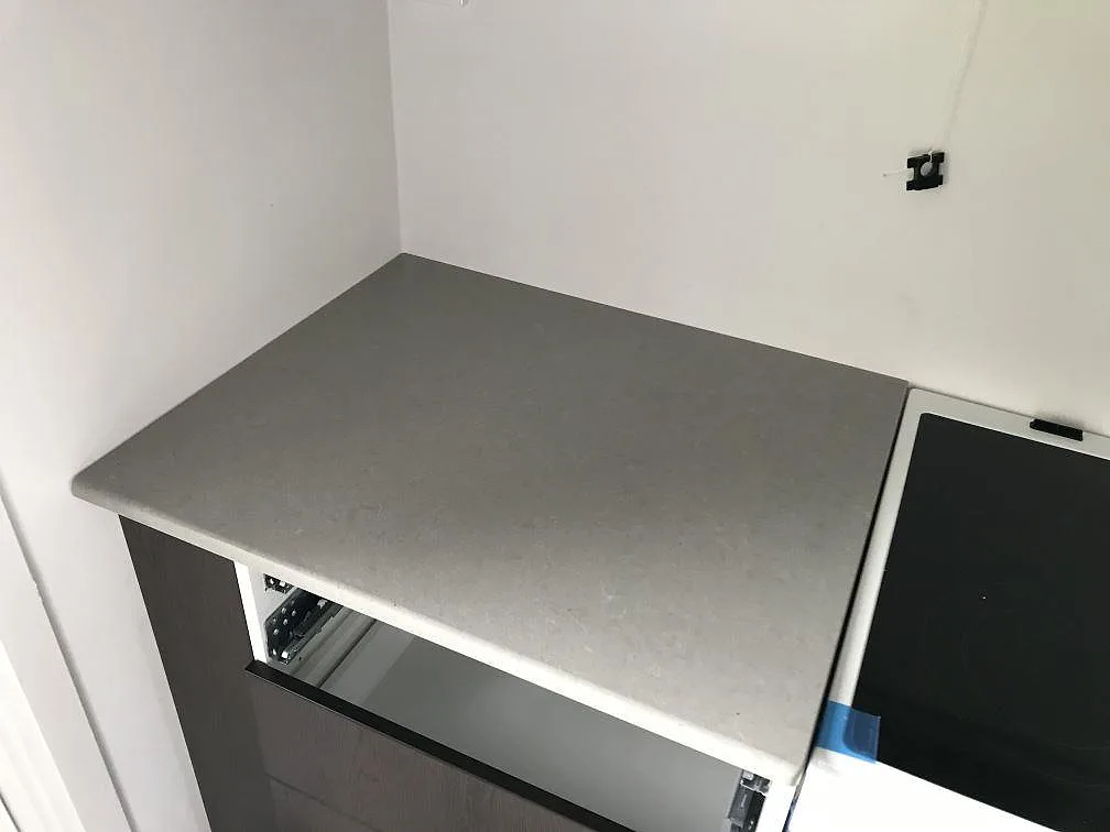 Detalj av Technistone Noble Concrete Grey-bänkskivan i grå komposit intill induktionshällen i ett kök i Kågeröd.
