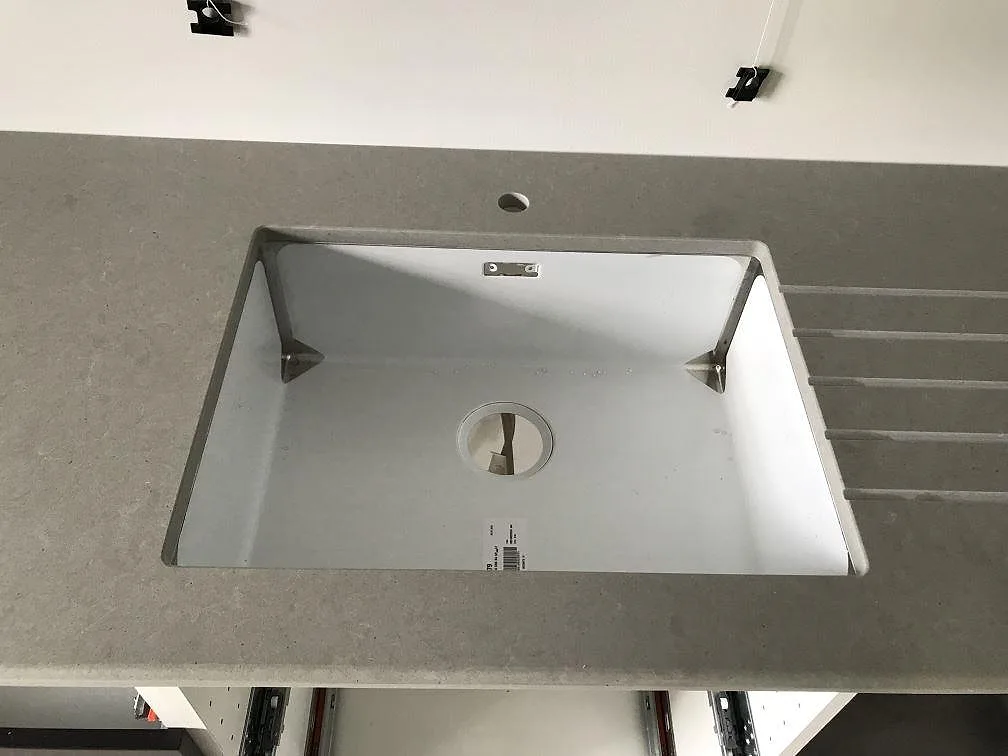 Underlimmad vit diskho i den grå Technistone Noble Concrete Grey-bänkskivan med urtag för köksblandare i Kågeröd.