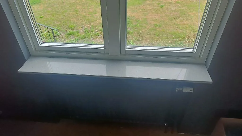 Smal fönsterbänk i grå Technistone Noble Concrete Grey vid ett fönster i ett hem i Kristianstad.