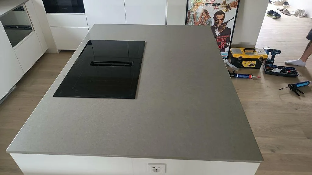 Köksö med grå betongtolkad bänkskiva i Technistone Noble Concrete Grey och svart induktionshäll, ovanifrån i ett kök i Kristianstad.