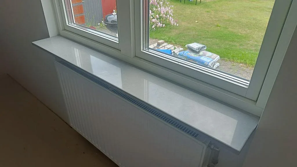 Polerad fönsterbänk i ljust grå Technistone Noble Concrete Grey ovanför en radiator i ett hem i Kristianstad.