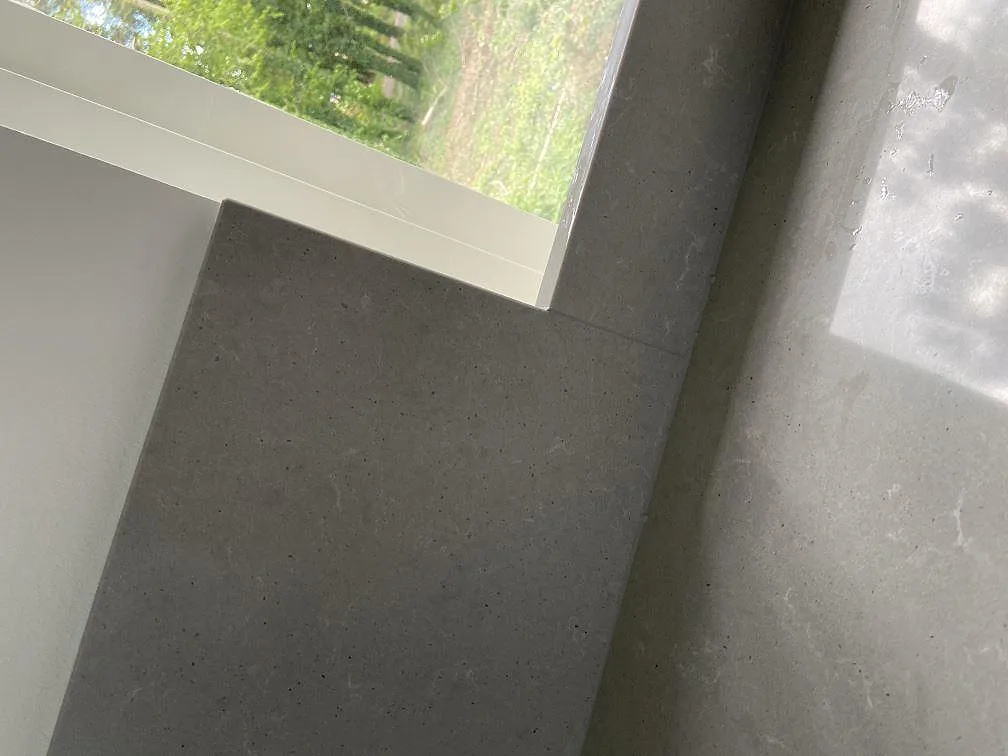 Närbild på den grå betongimiterande ytan i Technistone Noble Concrete Grey vid fönstersmygen i ett kök i Kristianstad.