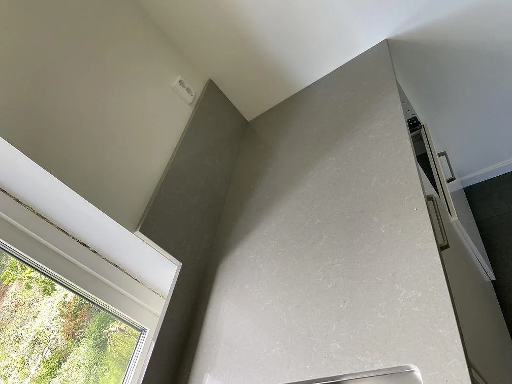 Köksbänkskiva i grå Technistone Noble Concrete Grey i ett hörn med fönster i ett kök under installation i Kristianstad.