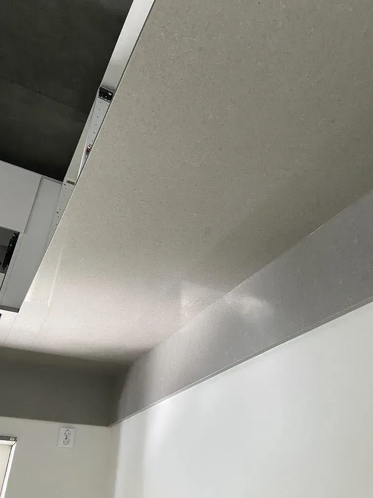 Grå Technistone Noble Concrete Grey köksbänkskiva med uppvikt stänkkant längs väggen i ett kök i Kristianstad.
