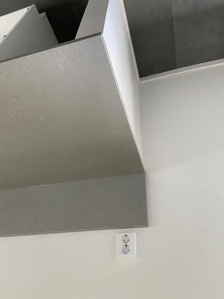 Grå Technistone Noble Concrete Grey köksbänkskiva med stänkkant och vägguttag i ett kök i Kristianstad.
