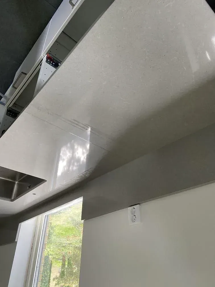 Polerad köksbänkskiva i Technistone Noble Concrete Grey med underlimmad rostfri diskho intill fönstret i ett kök i Kristianstad.