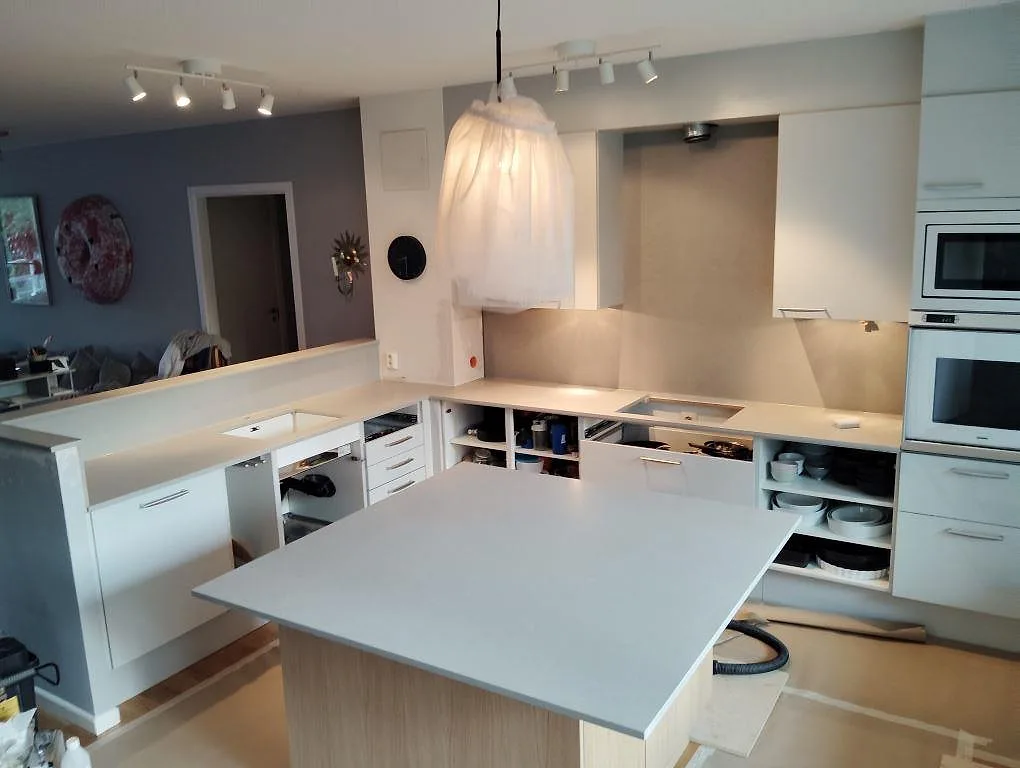 Köksbänkskiva i matt Technistone Noble Concrete Grey med stor köksö och väggbänkar under montering i Lidingö.