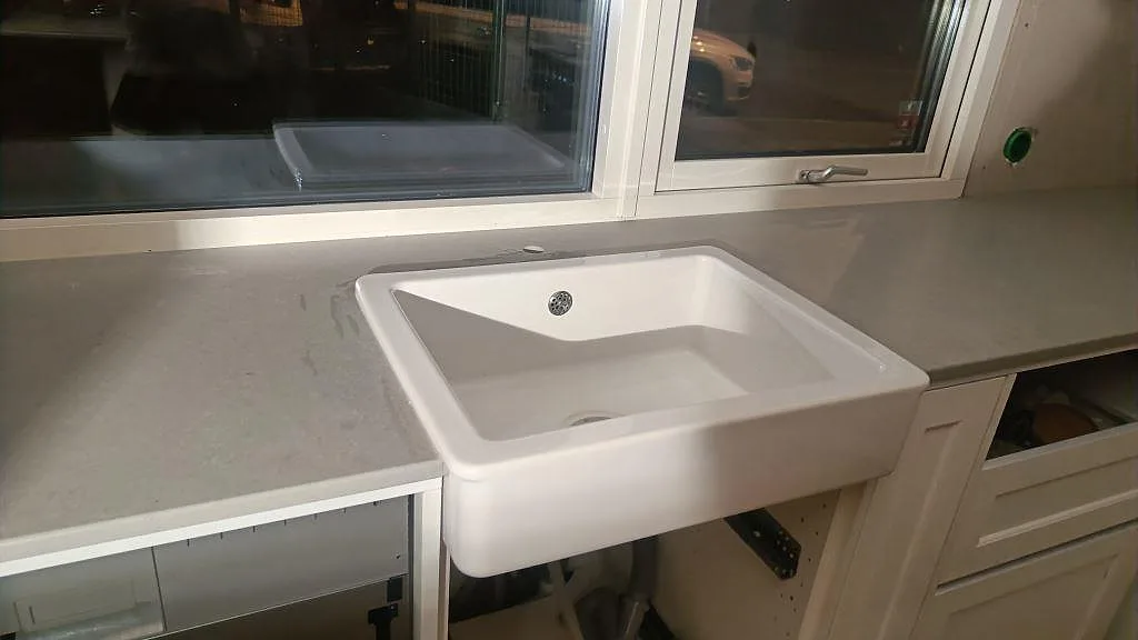 Närbild av matt Technistone Noble Concrete Grey med vit diskho och grå bänkyta i ett kök under montering i Limhamn.