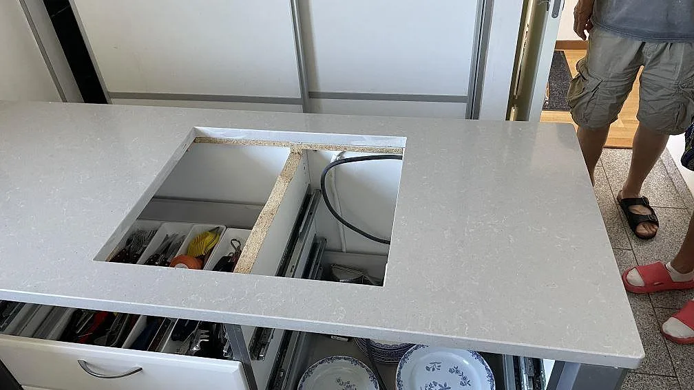Halvö i polerad Technistone Noble Concrete Grey kvartskomposit med stort rektangulärt urtag under montering i Limhamn.