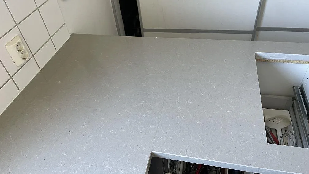 Ovanvy av polerad Technistone Noble Concrete Grey köksbänkskiva med grå melerad yta och större urtag i köket i Limhamn.
