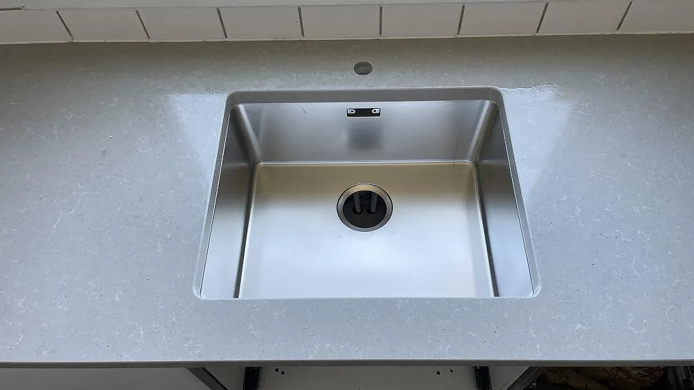Rostfri diskho i en polerad Technistone Noble Concrete Grey köksbänkskiva med ljusgrå melering i Limhamn.