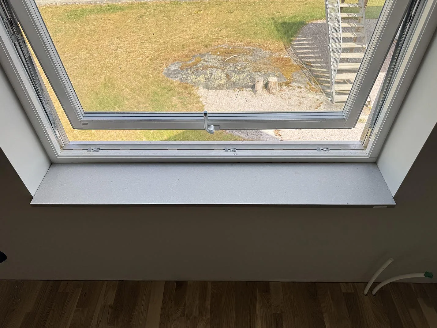 Fönsterbänk i matt Technistone Noble Concrete Grey, grå kvartskomposit, monterad vid öppet fönster i Listerby.