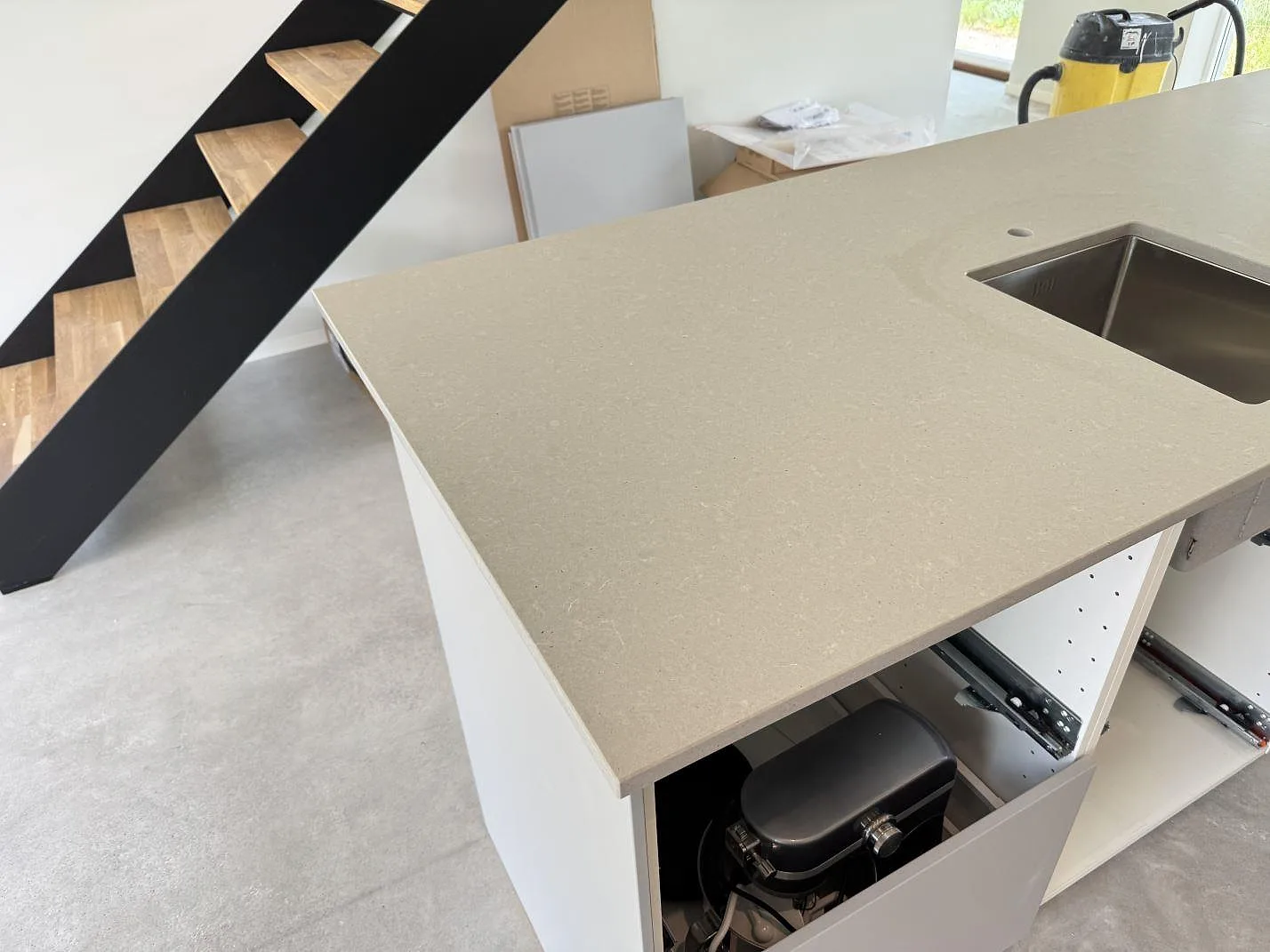 Köksö med bänkskiva i matt Technistone Noble Concrete Grey och synlig diskho utskuren i grå kvartskomposit i Listerby.