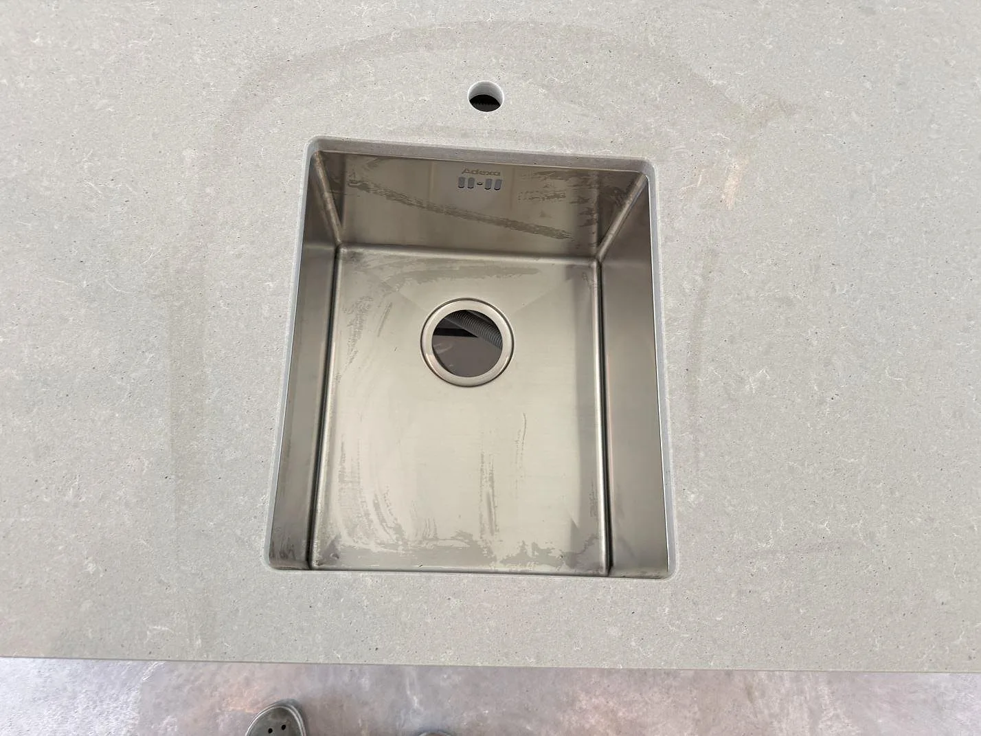Detalj av underlimmad rostfri diskho i bänkskiva av matt Technistone Noble Concrete Grey i Listerby.