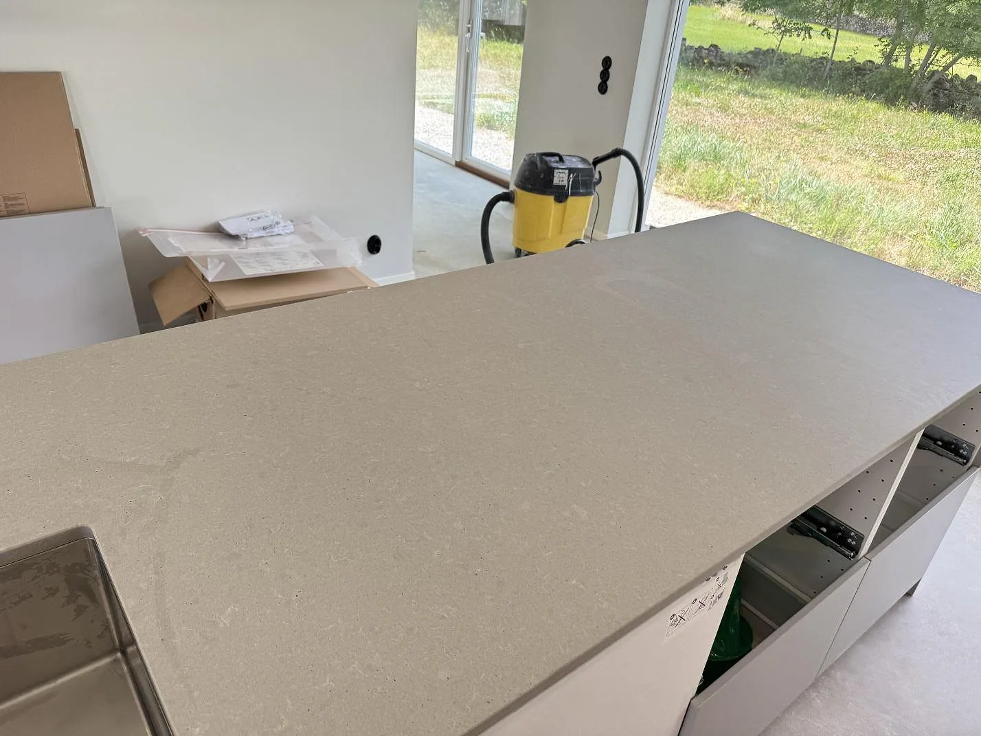 Närbild av matt Technistone Noble Concrete Grey på köksö med grå kvartskomposityta och rostfri diskho i Listerby.