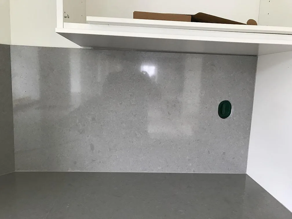 Polerat stänkskydd i Technistone Noble Concrete Grey i betongton med blank yta i ett kök i Löberöd.