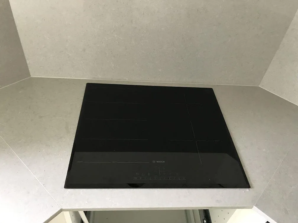 Infälld induktionshäll från Bosch i en köksbänkskiva av grå Technistone Noble Concrete Grey, polerad, i Löberöd.