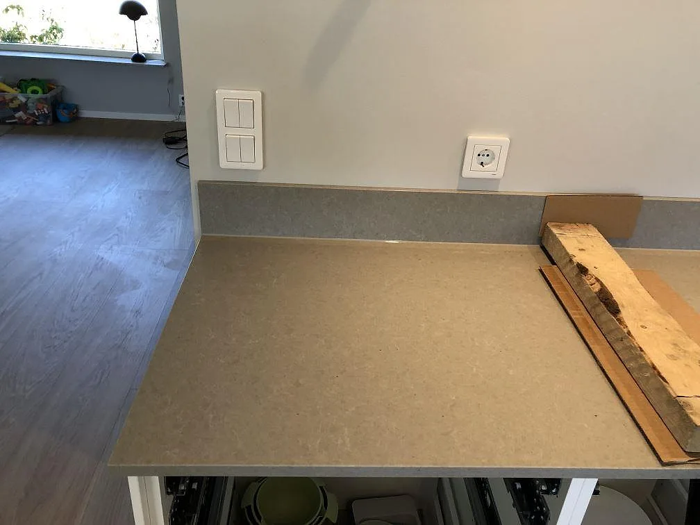 Bänkskiva i grå Technistone Noble Concrete Grey med uppvikt stänkkant mot vägg i ett kök under montering i Lomma.