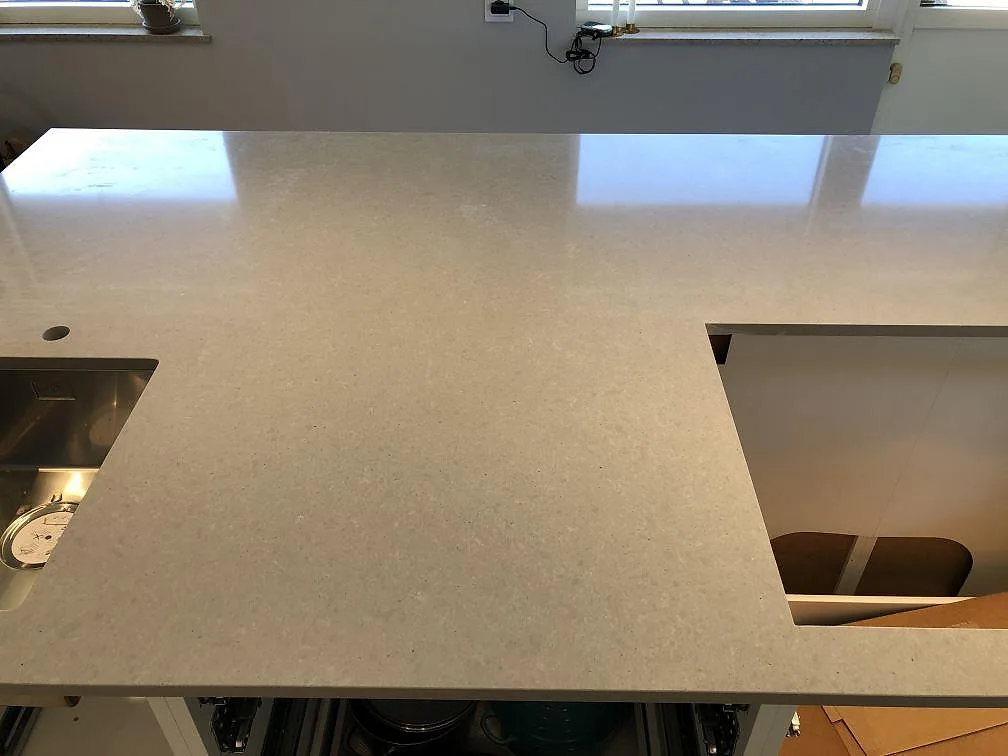 Köksbänkskiva i grå Technistone Noble Concrete Grey med underlimmad rostfri diskho och utsparning för häll i ett kök i Lomma.