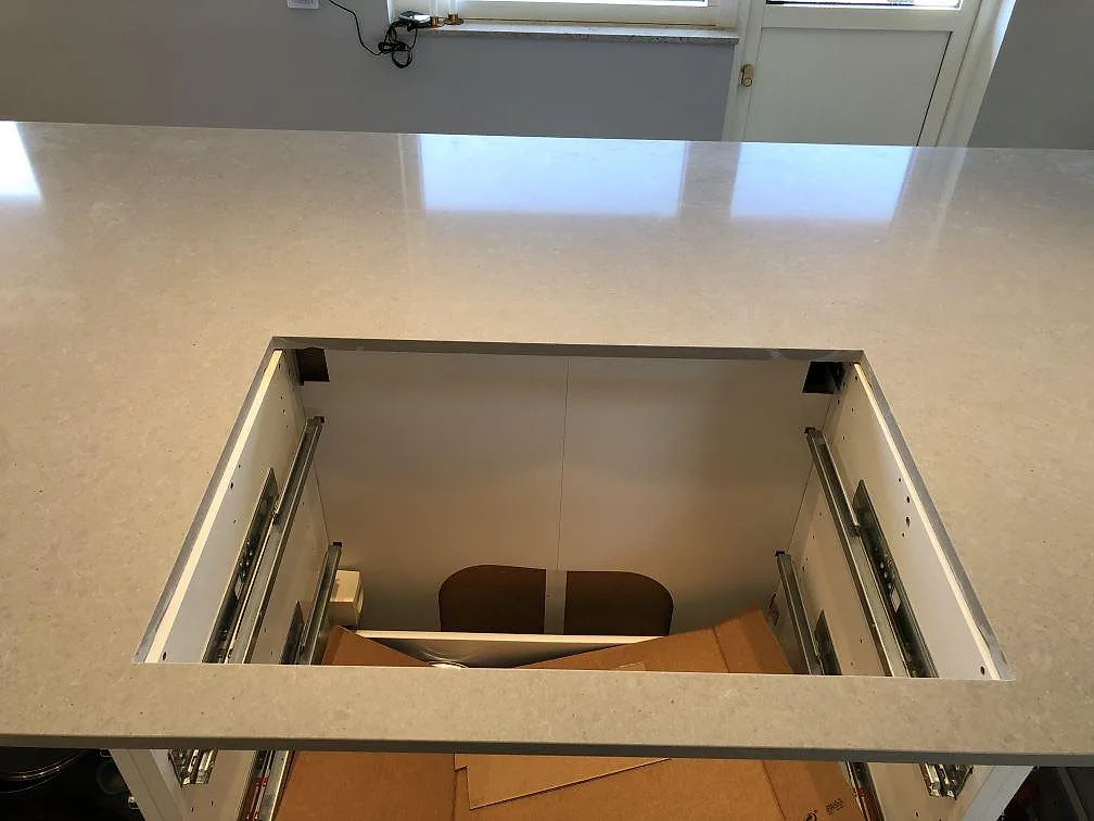 Polerad köksö i grå Technistone Noble Concrete Grey med utsparning för diskho över öppna stommar i ett kök i Lomma.