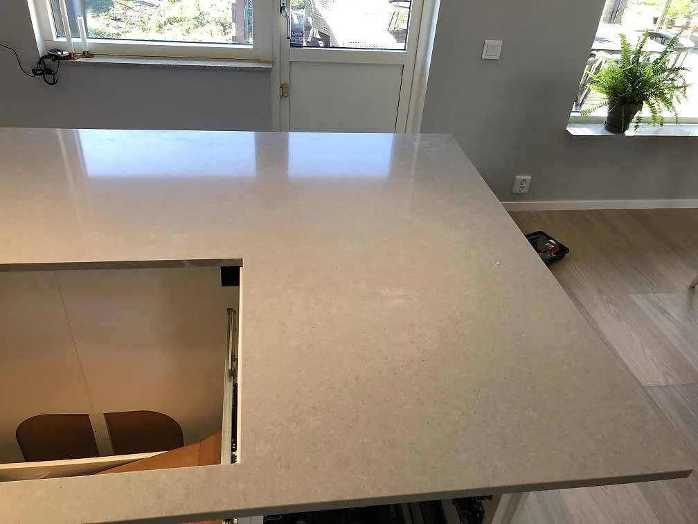 Polerad köksö i grå Technistone Noble Concrete Grey med utsparning för diskho, installerad i ett ljust kök i Lomma.