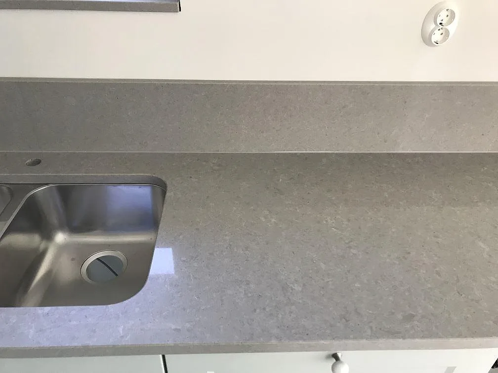 Underlimmad rostfri diskho och förborrat blandarhål i grå Technistone Noble Concrete Grey köksbänkskiva i ett kök i Lund.